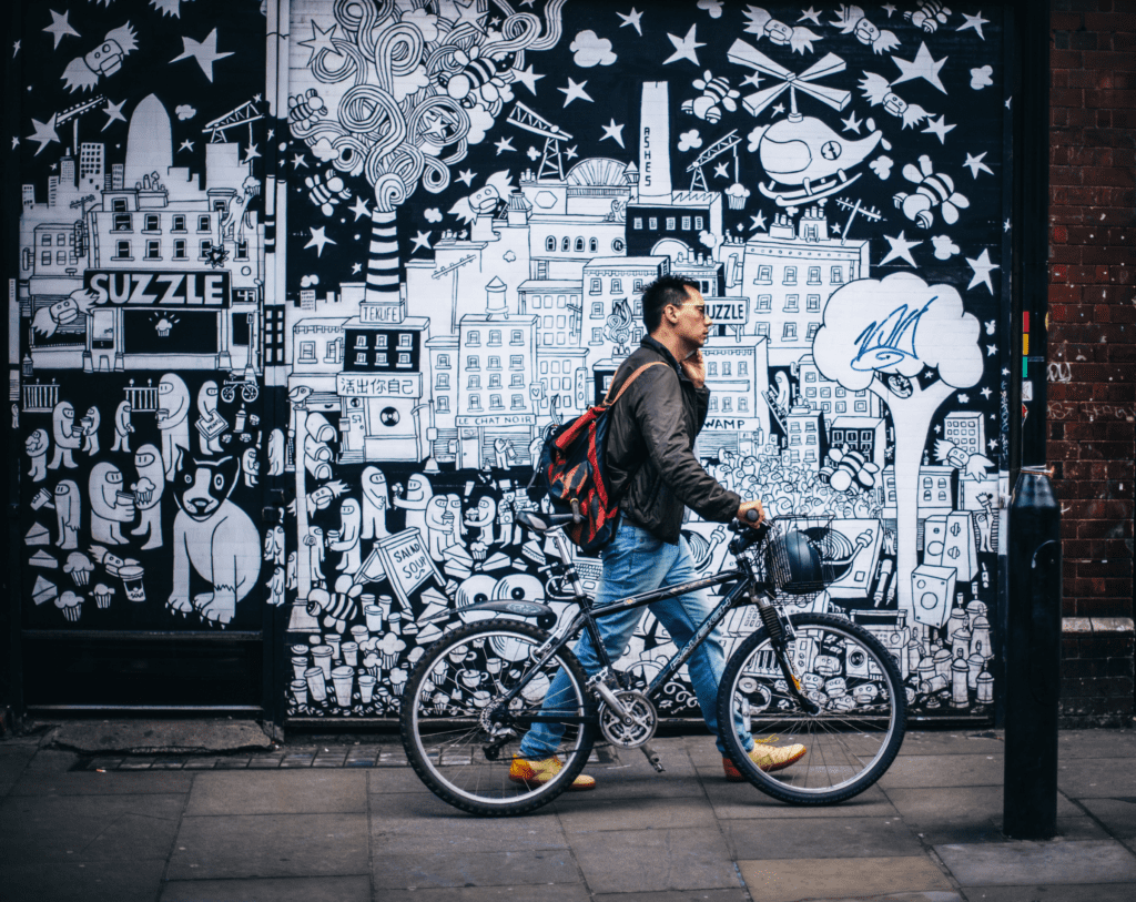 Homem com sua bicicleta na cidade. Foto de Clem Onojeghuo na Unsplash.