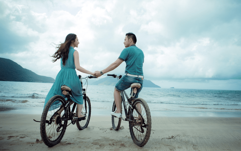 Casal passeando de bicicleta pela praia. Foto de formulário PxHere.
