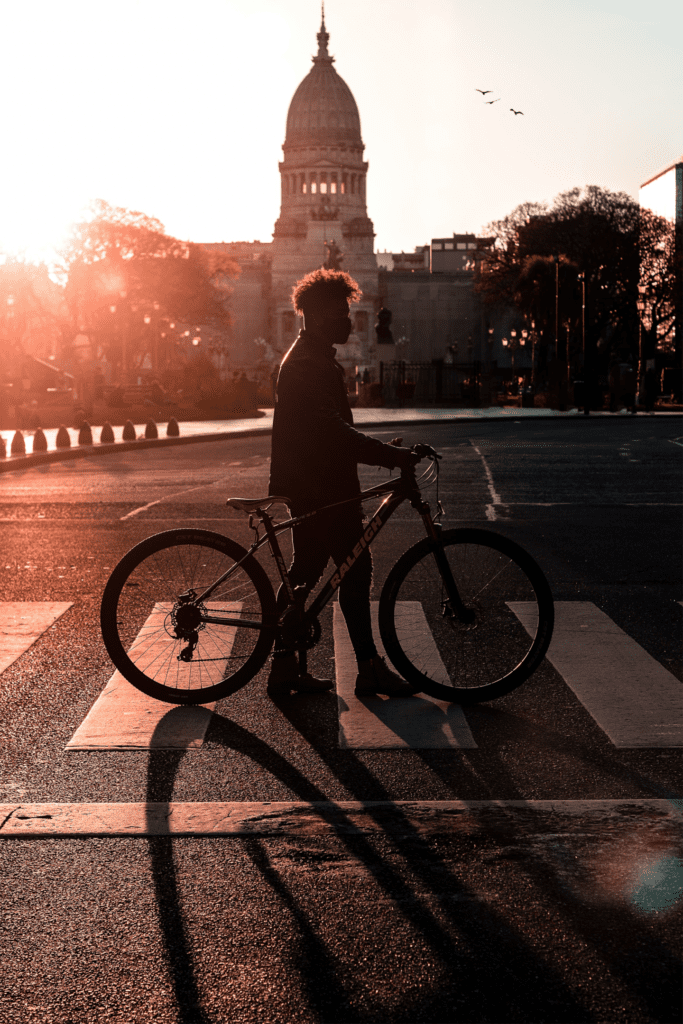 Ciclista andando com sua bicicleta pela cidade. Foto de Alex Umbelino, Pexels.