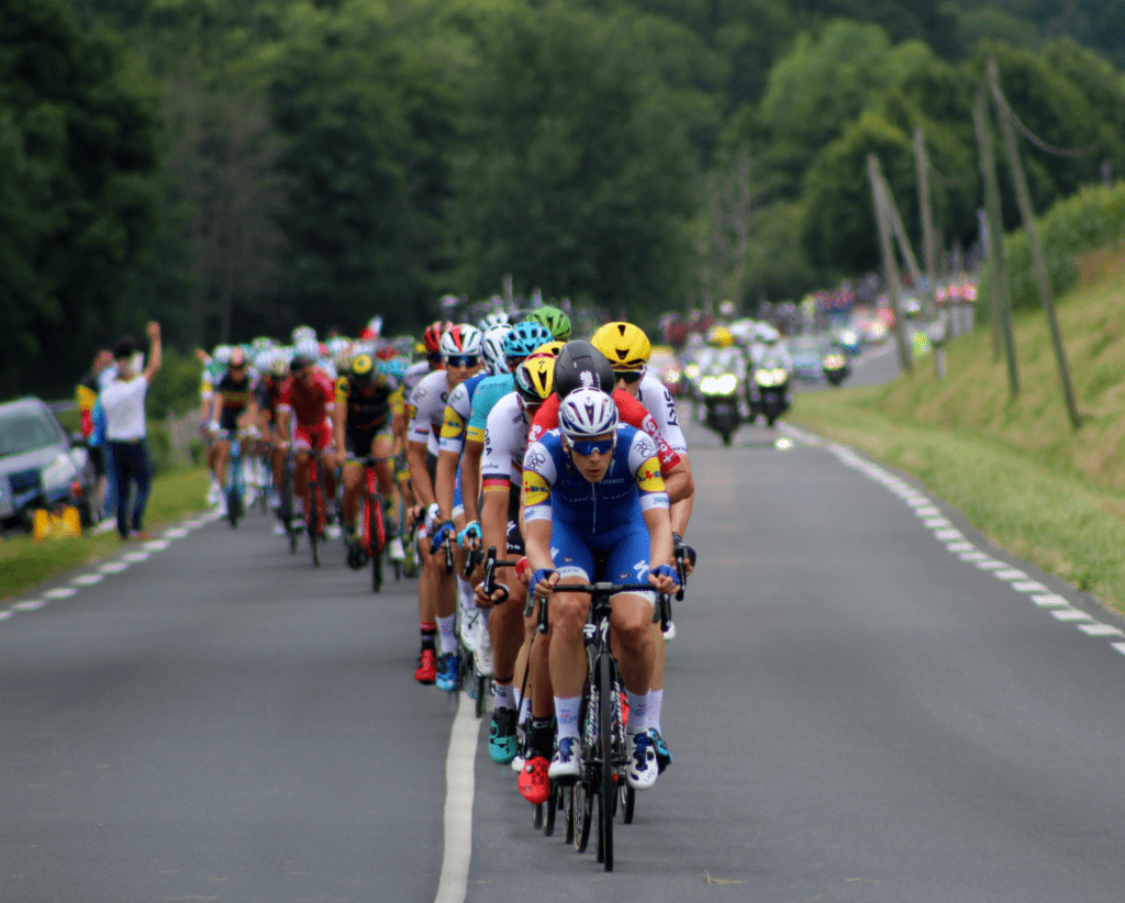 Competidores em prova de Tour de France. Foto de Rob Wingate, Unsplash.