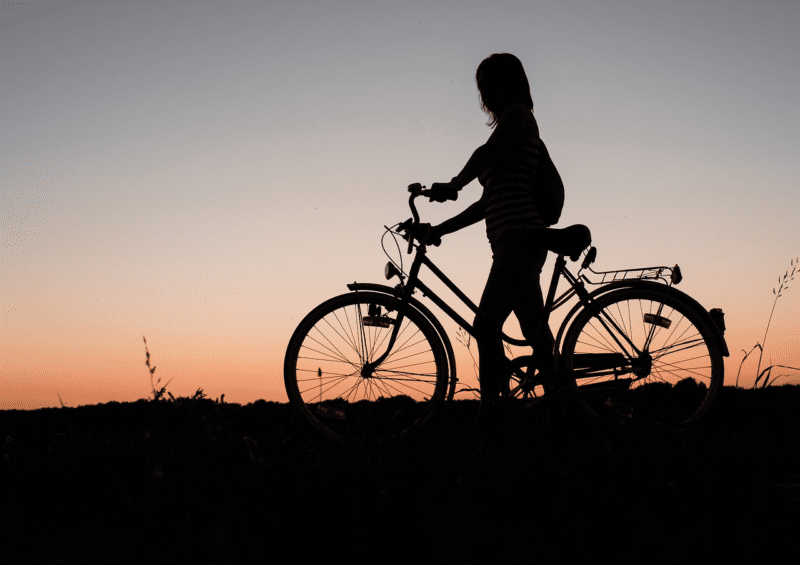 Mulher segurando a bicicleta - Fonte: Pixabay.