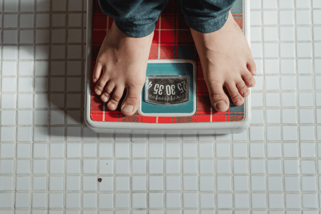 Pessoa se pesando na balança - Fonte: Pexels